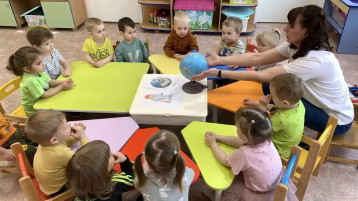 Воспитатель показывает детям группы "Маргаритка" глобус.