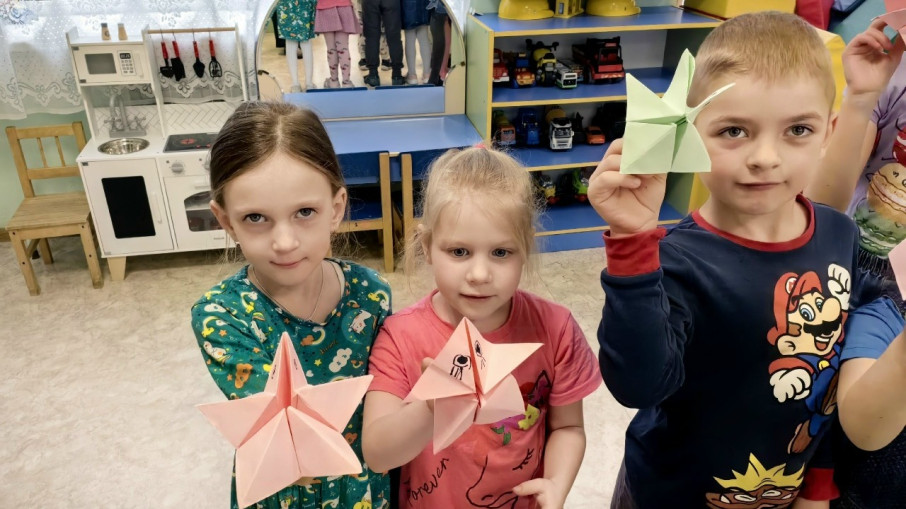 Две девочки и мальчик показывают звезды, сконструированные из бумаги.